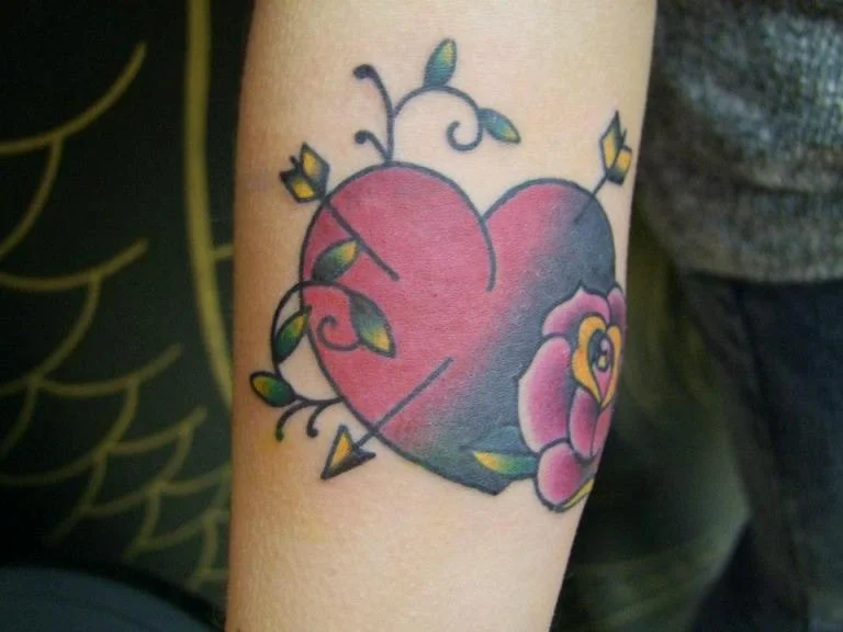 Red ink heart tattoo on dark skin tone
