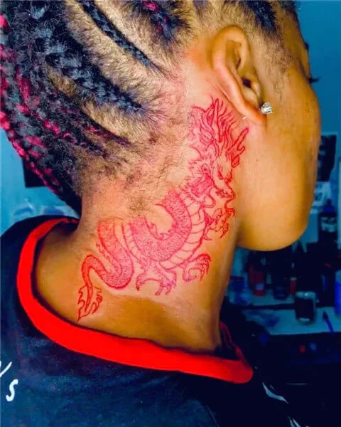 Red ink dragon tattoo on dark skin